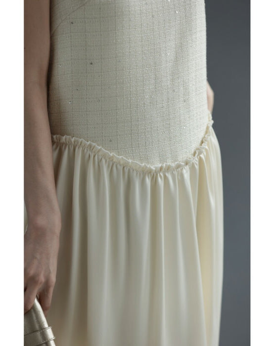 A dress with a tweed-like top and a glossy skirt, sparkling with sequins