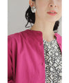 A collared shirt top with ruffles flowing from the back