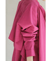 A collared shirt top with ruffles flowing from the back