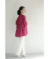 A collared shirt top with ruffles flowing from the back