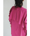 A collared shirt top with ruffles flowing from the back