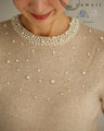 A bell-sleeve knit top with pearls falling all over it