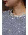 A bell-sleeve knit top with pearls falling all over it