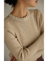 A bell-sleeve knit top with pearls falling all over it
