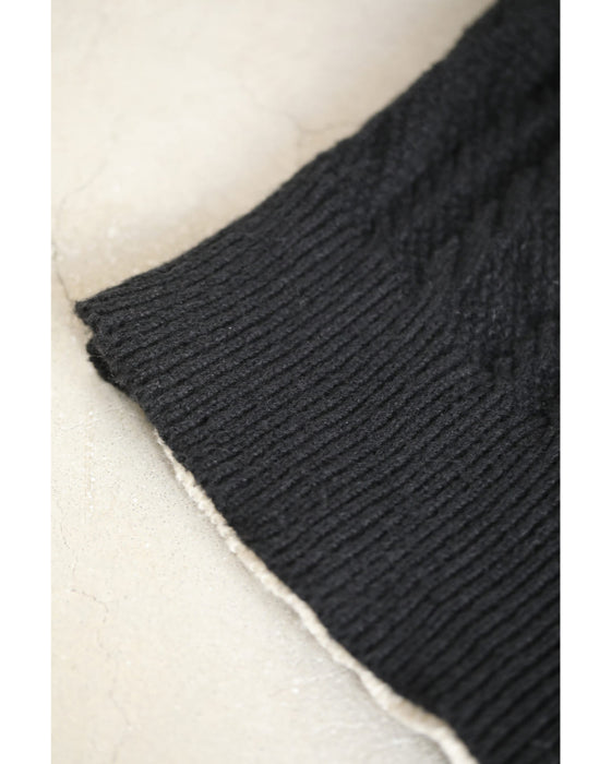 A knit pullover top with a black and white cache-coeur design