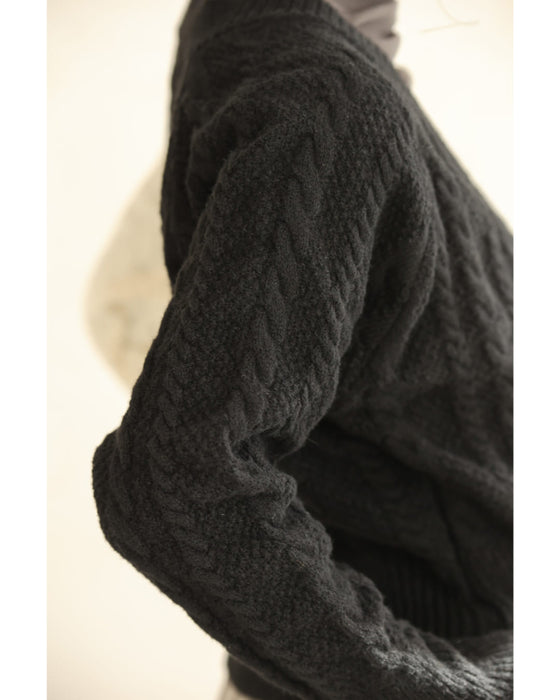 A knit pullover top with a black and white cache-coeur design